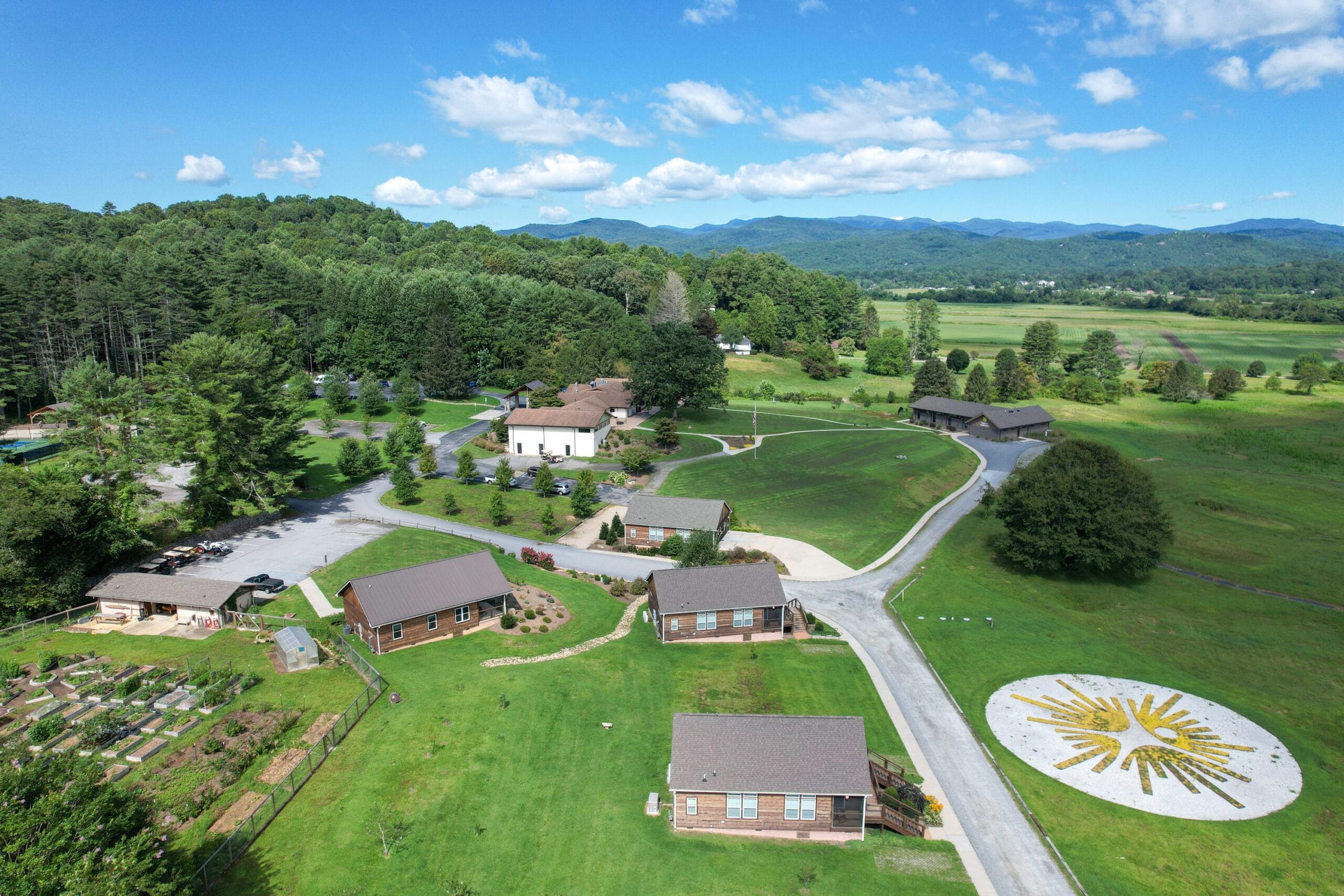 Aerial view of the Skyterra campus with the sunburst logo on the lawn and the Blue Ridge Mountains behind